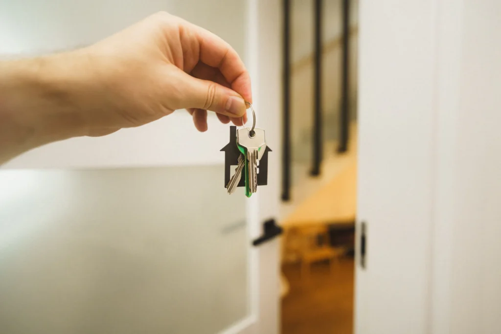 Hand holding a set of keys beside an apartment door